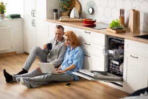 Moderni virtuvė su energiją taupančiais buitinės technikos prietaisais – šaldytuvu, skalbykle ir indaplove.