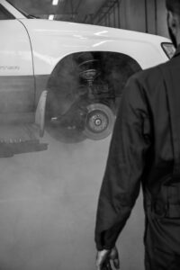 Profesionalus mechanikas tikrina automobilio pakabą techninės apžiūros pasiruošimo metu autoservise.